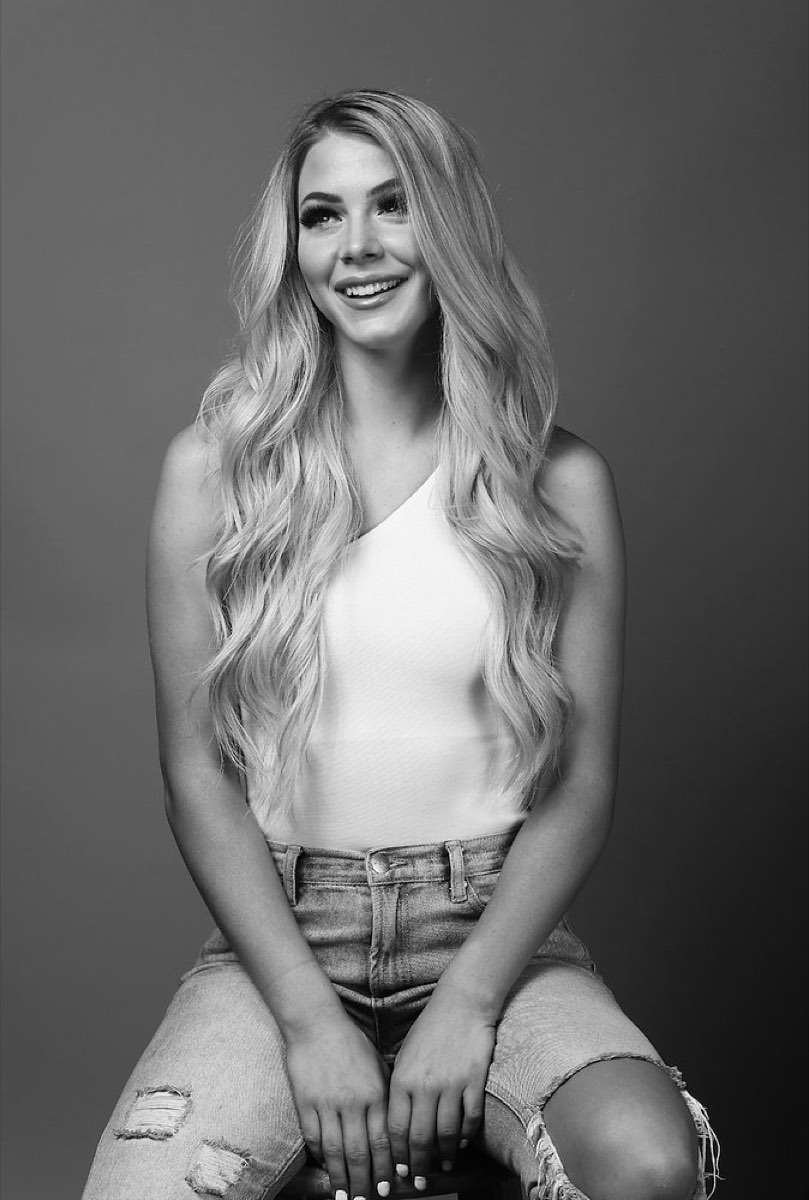 Long blonde tape-in hair extensions worn in loose waves, black-and-white studio portrait